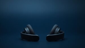 Modern wireless headphones with visible sensors positioned on clean navy studio background with soft professional lighting highlighting the premium materials and technological details in horizontal composition
