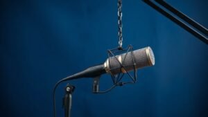 Professional shock mount holding a large diaphragm condenser microphone against clean navy blue studio background with soft side lighting creating gentle shadows on the elastic suspension bands and metal frame