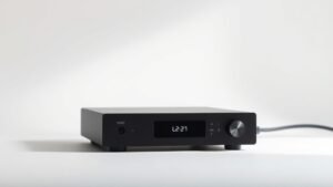 Modern DAC unit on clean white studio background with soft side lighting. Sleek black rectangular device with minimal LED indicators and single USB cable. Professional product photography with shallow depth of field.