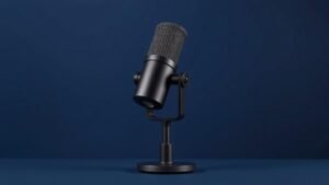 A single professional dynamic podcast microphone mounted on a sleek adjustable desk stand, positioned at a slight angle against a clean deep navy background. Soft diffused side lighting catches the matte black cylindrical body and metal mesh grille, casting a gentle shadow across the surface below. The composition is centered and balanced, emphasizing the microphones refined industrial design and broadcast-ready build quality.